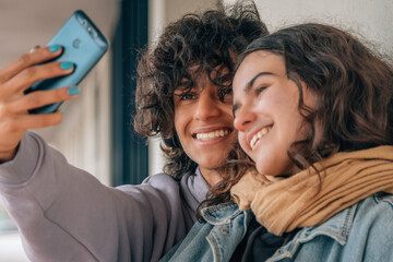 teenage couple making a live video or selfie with phone on the street