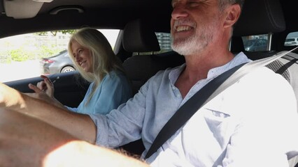 Happy senior mature couple driving their car, dancing to music and singing