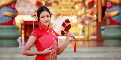Portrait of young asian woman with traditional Chinese red drese, standing smilling holding angpao...