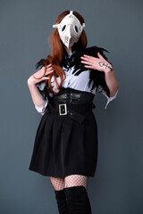 Female cosplayer dressed as a plague doctor with a white mask.