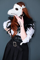 Female cosplayer dressed as a plague doctor with a white mask.