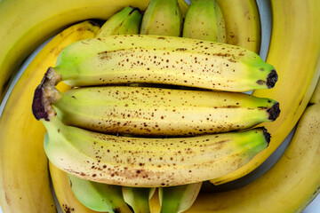 Top view of a bunch of green bananas. Banana skin has dark spots. The flesh of the fruit is soft, sweet. Nutrition and healthful. Taiwan food and agriculture concept.