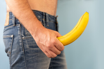man's hand holds a banana on the background of a fly, close-up. Potency concept, impotence, male...