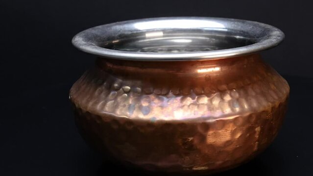 Classic metal Copper brass bottom cooking pot shake rotate on black background
