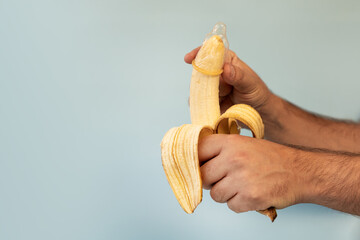 Hand shows how to put a condom on the penis using a banana as demonstration. concept of protection...