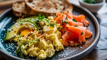 Foto op Plexiglas A gourmet breakfast plate on a dark wooden table. The plate contains fluffy scrambled eggs, fresh smoked salmon slices, and ripe avocado slices garnished with herbs and spices.  © Andrey