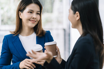female colleague of half Asian descent holds a cup of coffee and smiles happily.