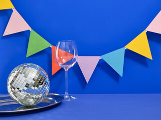 A glittery disco ball and wineglass on a blue background. Copy space for text. Decorative beautiful...