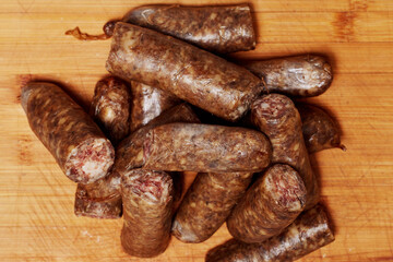 Homemade sausages cut into pieces placed on a wooden chopper.