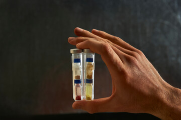 scientist hand holding test tubes between fingers for
experiment with air-sensitive iridium-gold complexes in a Schlenk flask - obrazy, fototapety, plakaty