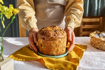 Female hands putting Easter cake on the table. Traditional easter cake or sweet bread with topping....