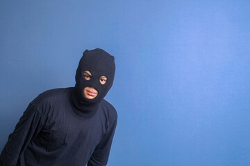 Man burglar wear black balaclava and black sweater looking at camera with angry expression