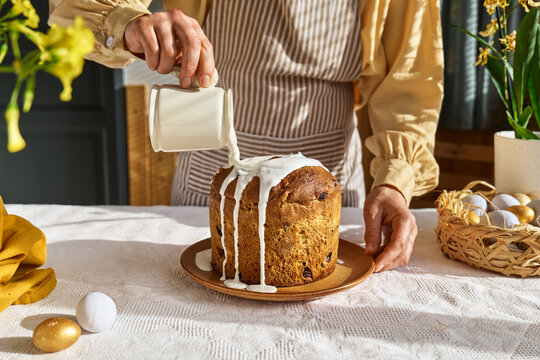 Female hands pouring icing on Easter cake. Traditional easter cake or sweet bread with topping. Easter treat.