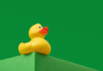 Yellow rubber duck on a green background. Copy space for text. Fun bath toy.