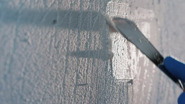 Builder's hand with putty knife, putty on a white wall