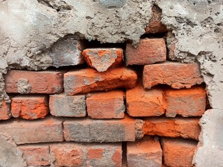 Damaged plaster exposed broken brick wall