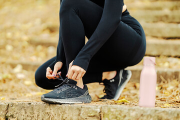 Close up of an unrecognizable sportswoman tying shoelace in nature.