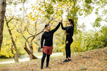Happy fitness couple is giving high five each other for teamwork while standing in nature.