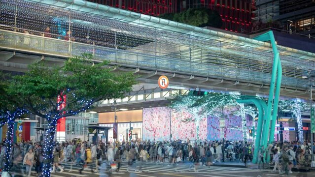 Time-lapse shot of unrecognizable people walking on the road.  Tourists stroll through the famous shopping and tourist area of ​​Xinyi District, Taipei.