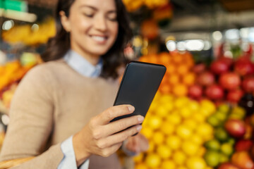 A woman using a phone at farmers market, selective focus on hand.