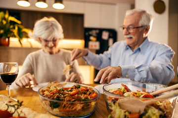 Selective focus on food on a table with senior couple eating in blurry background.