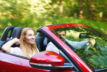 Couple in red cabriolet in a sunny day