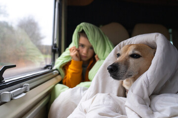 Boy with his dog in the bed of a motorhome covered with duvets
