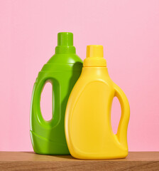 Laundry detergents in green and yellow bottles for clean and fresh clothes on a wooden table.
