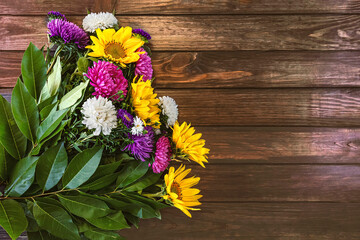 Bouquet of autumn flowers background. Flowers of colorful asters and yellow sunflowers on a dark wooden background. Place for text