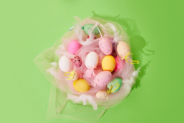 Multicolored painted Easter eggs lying in circle in pink fabric over green background. Concept of Easter holiday, celebration, traditions, happiness. Postcard. Empty space for ad