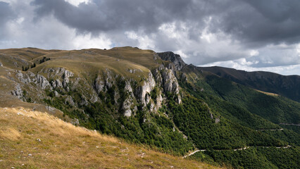 Mountain overgrown in grass with rocky cliffs and slopes covered with low bushes during cloudy day, Vlasic mountain near Travnik
