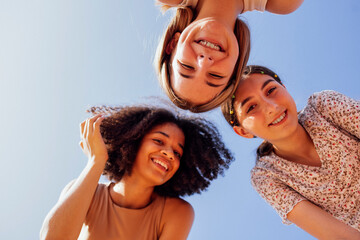 Funny multiracial smiling teenager gilrs standing and looking down at camera. Group of happy...
