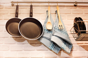 Utensils and pans hanging on railing above counter