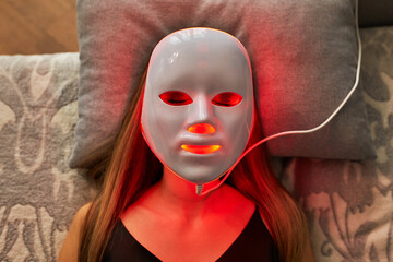 Woman with led light therapy facial beauty mask photon therapy. Home skin care