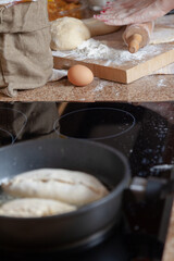 Women hands roll out dough in frying pan foreground ....