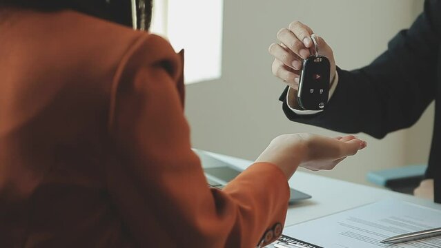 Insurance officers hand over the car keys after the tenant. have signed an auto insurance document or a lease or agreement document Buying or selling a new or used car with a car
