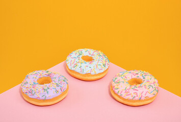 Three sweet, fresh donuts with bright sprinkles on the table. Sweet collection.