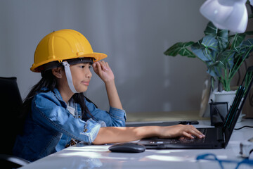 Cute Asian girl thai happy kid wearing yellow construction or safety hard hat, working  with a...