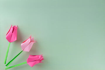 Handmade pink tulips made of colored paper on a green background. Mother's day, women's day concept.