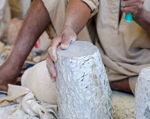 hands of a male Egyptian sculptor while working with a stone alabaster