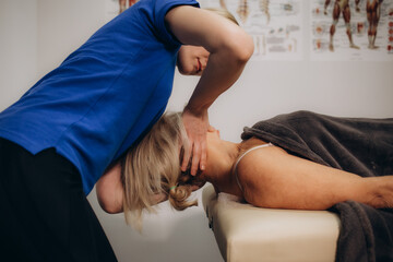 Physiotherapist helping senior woman with elbow exercise in clinic. Doctor checking elbow of senior patient. Woman during an appointment with professional osteopath working