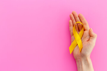 Yellow ribbon symbol of bone cancer with hands. Medical support and prevention