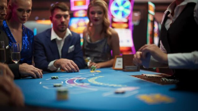 Portrait of a Newly Rich Man Winning at a Blackjack Table Card Game in a Modern Casino. Cinematic Shot of a Group of Exclusive Club Guests Celebrating a Lucky Bet and Victory