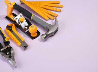 Set of various construction tools. Planer, hammer, yellow utility knife, folding ruler on a purple...