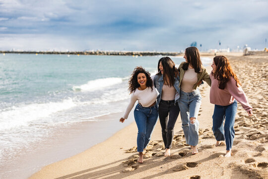 Friends of various ethnicities walk on the beach gossiping near the coast on their vacation