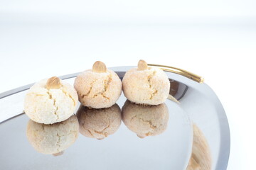 Tipici biscotti sardi morbidi alle mandorle, sul tavolo una piastra in acciaio lucido, spazio per copiare il testo.