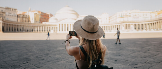 Young attractive smiling girl tourist exploring new city at summer
