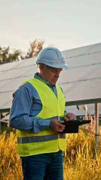 Inspector engineer man holding digital tablet working in solar panels power farm