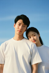 An asian young couple, shot in the studio with blue sky background.