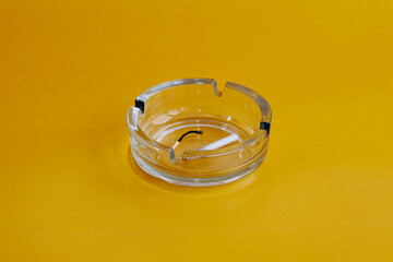 Ashtray with cigarette butt and burnt match on yellow background